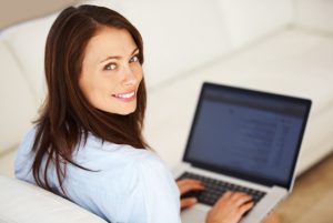 Portrait of beautiful business woman using laptop while looking at you